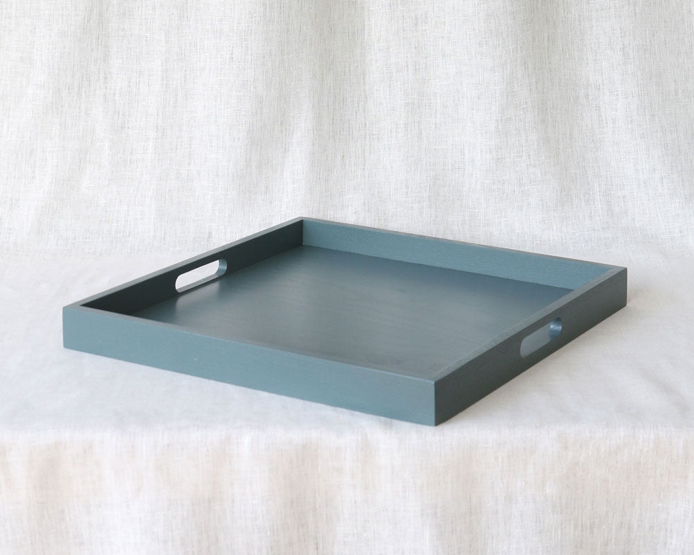 Diagonal angled view of the blue-grey ottoman tray showing both side handles and depth of the tray walls.