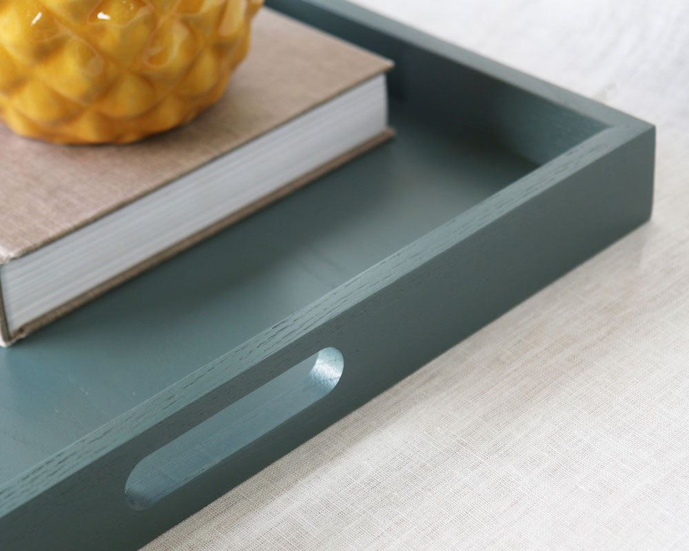 Detail view of the tray handle with a book and planter inside, showing the smooth finish and craftsmanship.