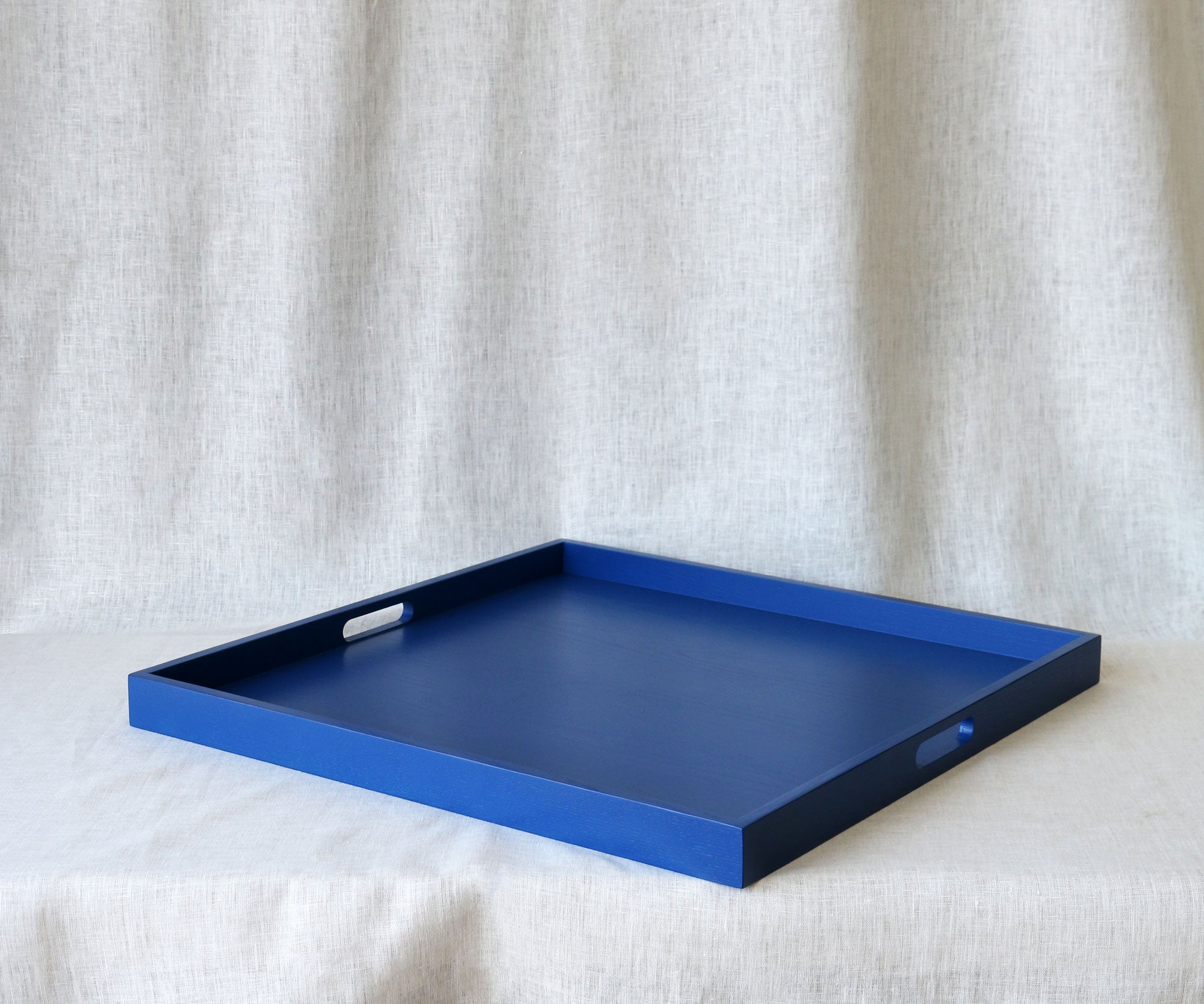 Blue tray with handles on a textured white surface