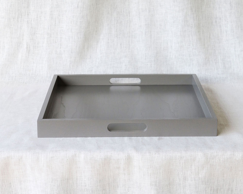 Straight-on view of an empty grey ottoman tray showing both side handles, against a neutral background.