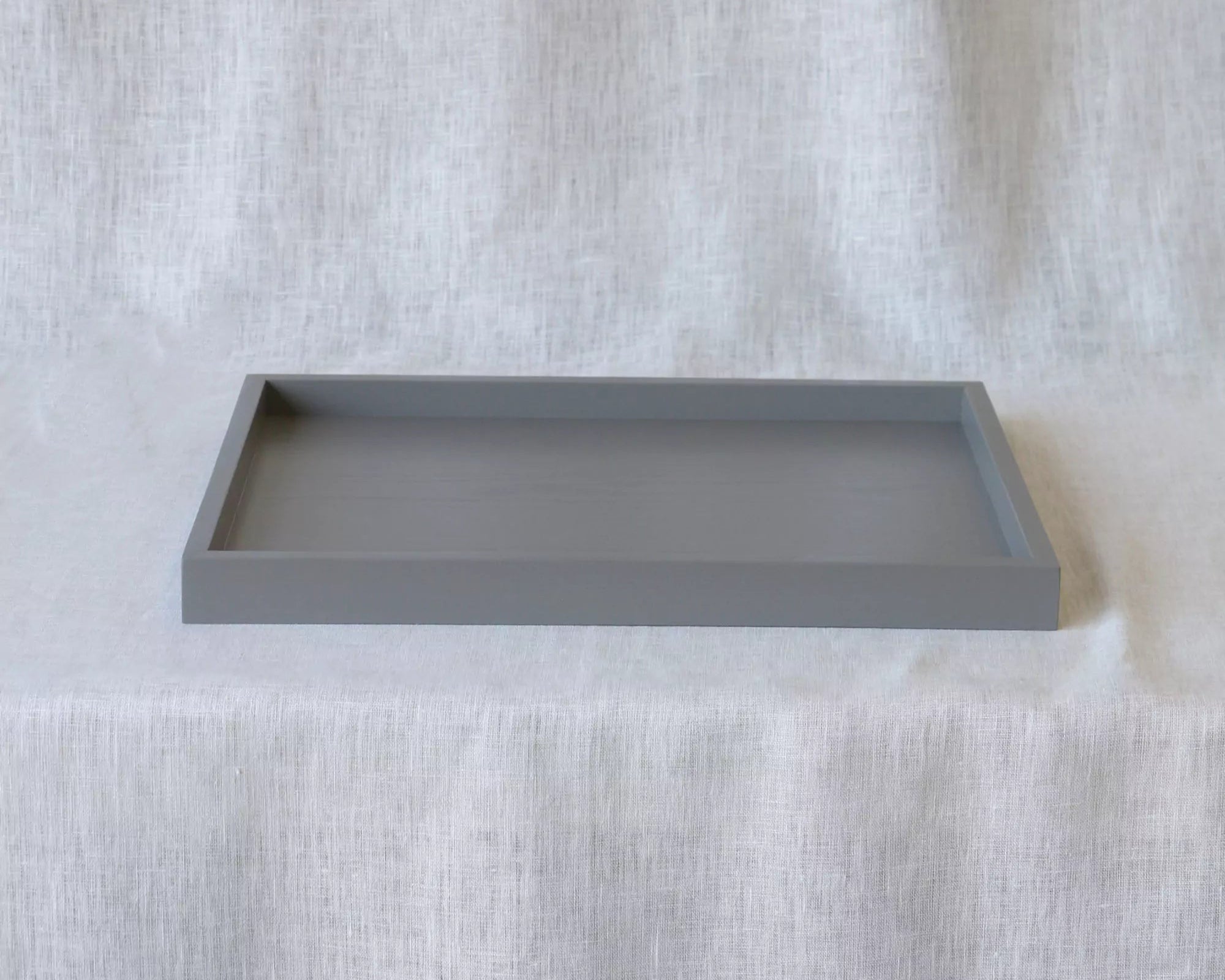 Gray rectangular tray on a textured white surface