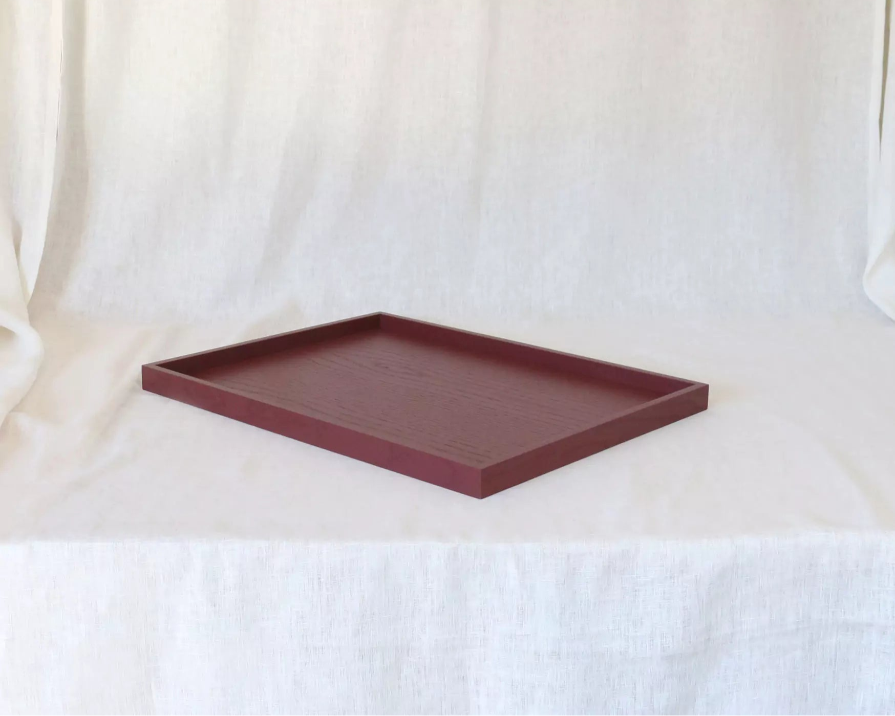 Maroon rectangular tray on a white curtain background