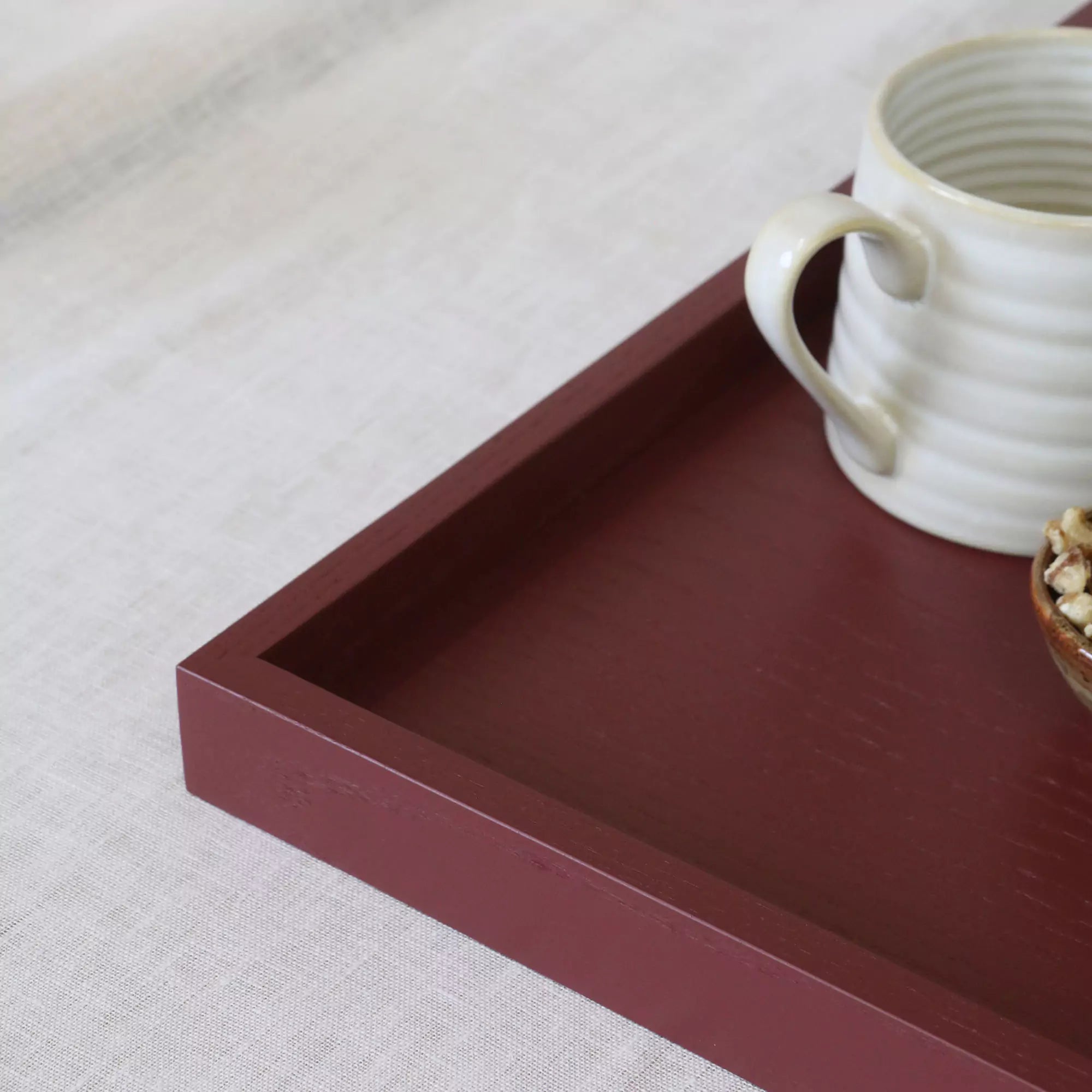 Red tray with a white ceramic cup on a light gray surface