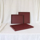 Three maroon trays on a white background