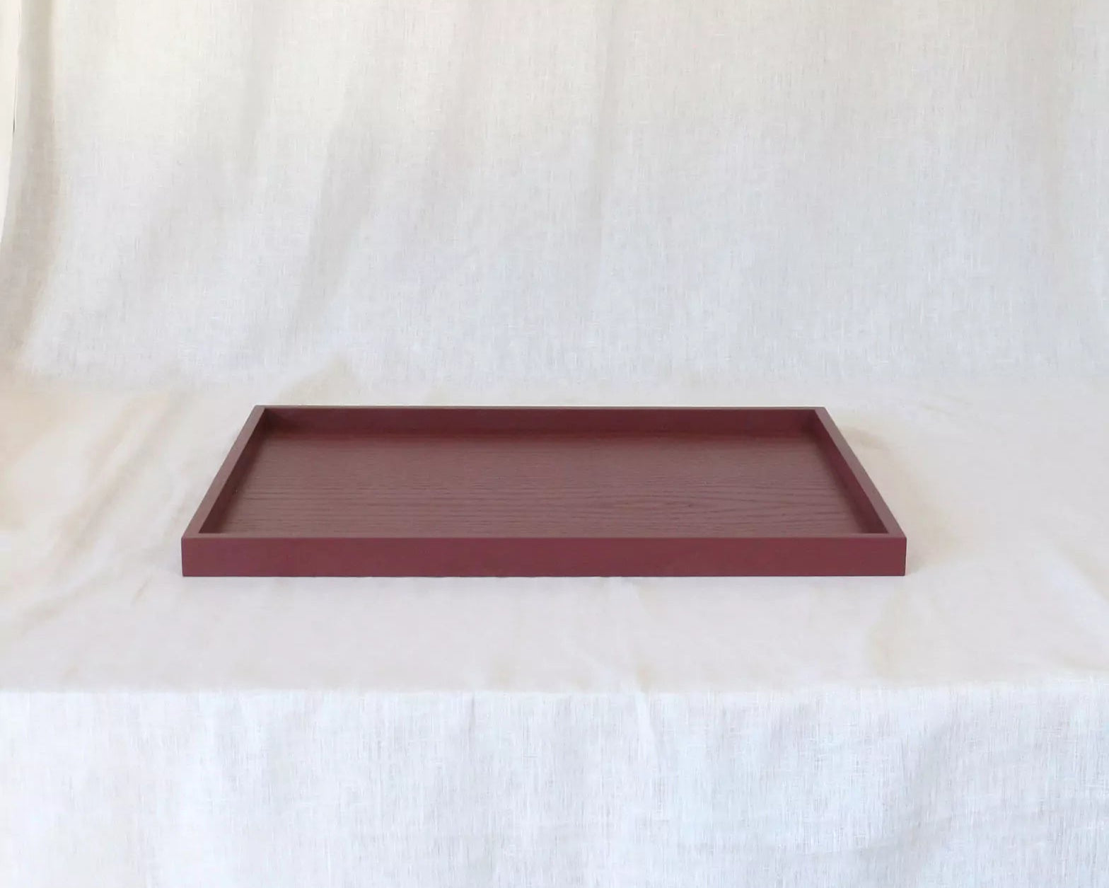 Maroon rectangular tray on a white fabric background
