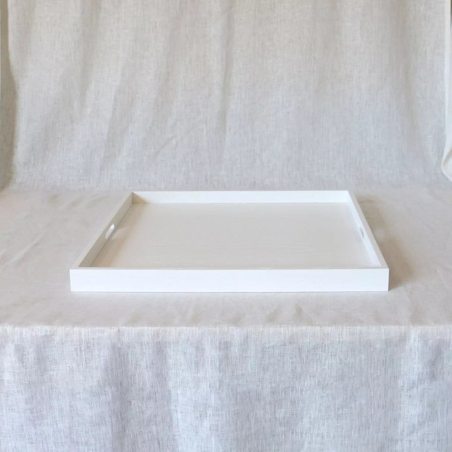 white serving tray with handles on a linen curtain backdrop