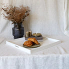 Tray with pastries and a vase of dried flowers on a white tablecloth.