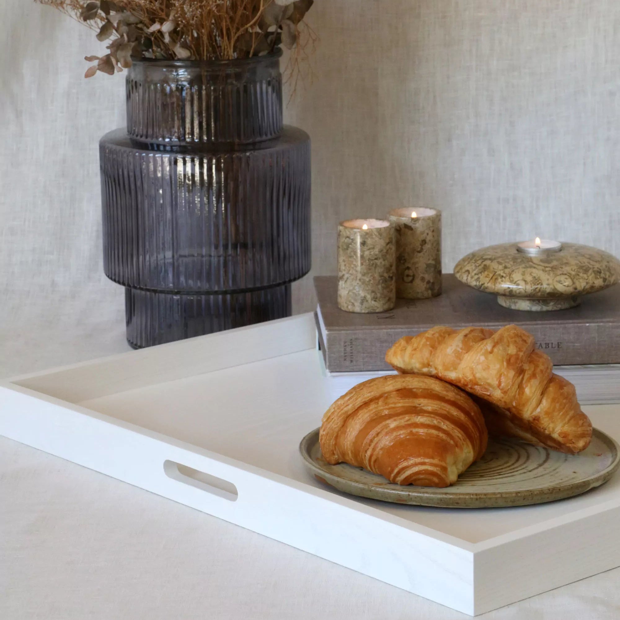 Baked goods on a tray with a vase and candles in the background