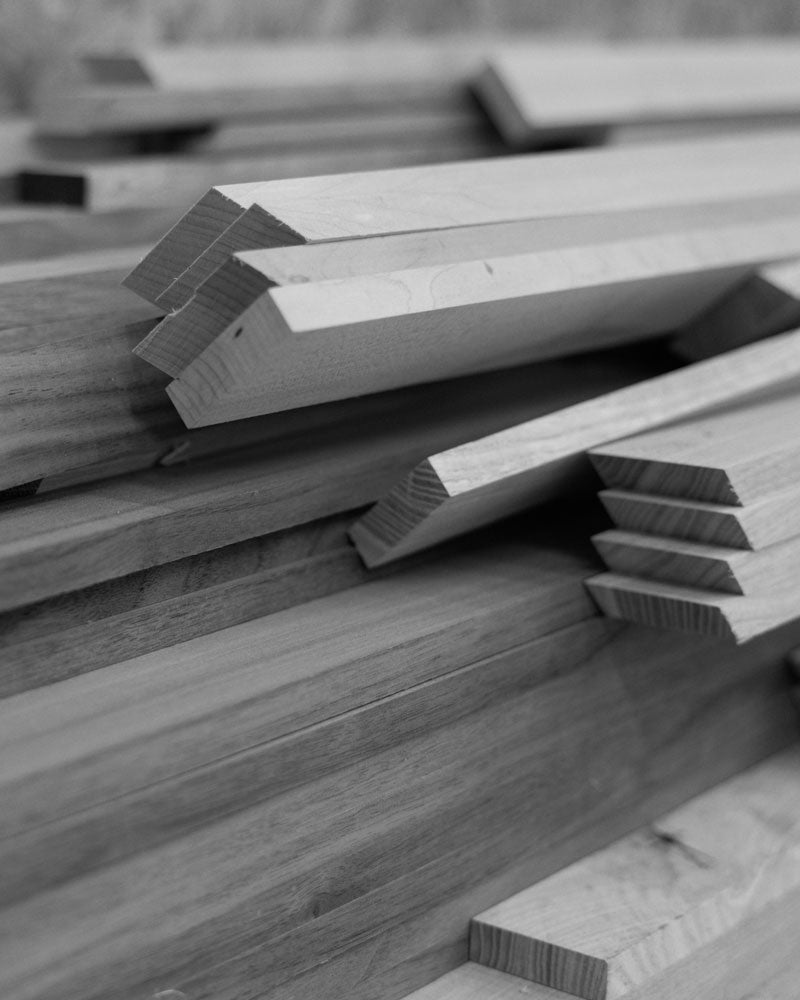 A close-up view of precisely cut wooden planks stacked in a woodworking studio, showcasing their smooth finishes and angled edges, ready for assembly.