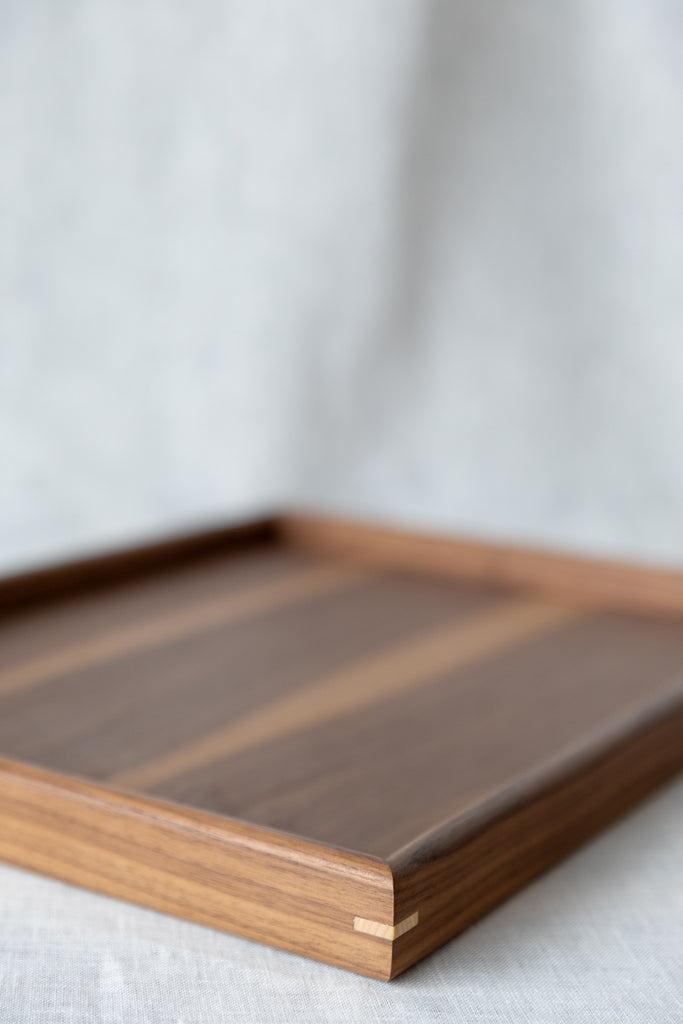 Close up image of the walnut serving tray and contrasting maple corner pin detail.