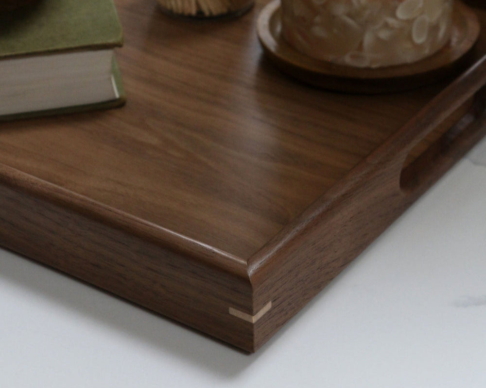 A handcrafted wooden tray styled in a modern kitchen with a mortar and pestle, a glowing candle, and rustic decor elements.