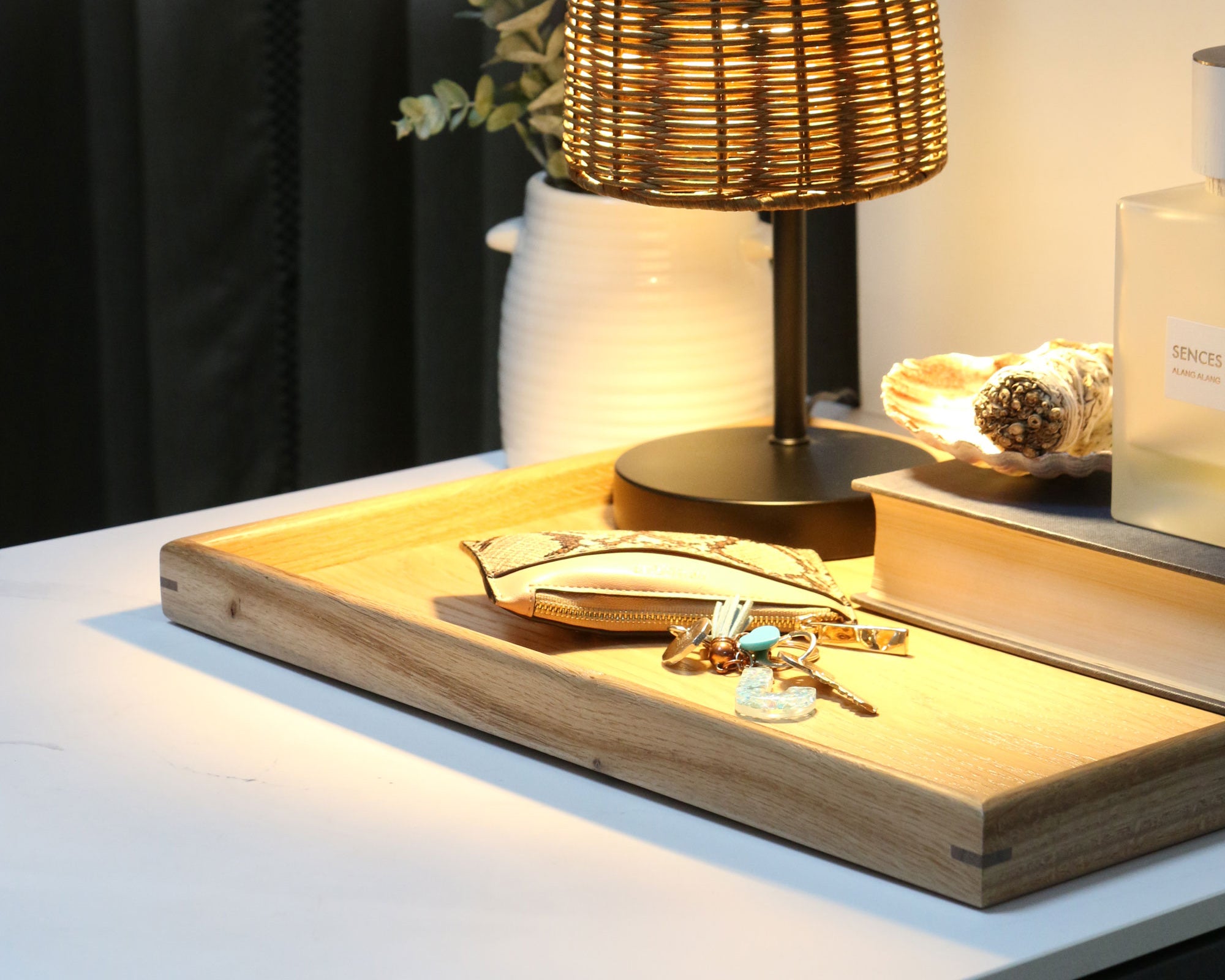 A handcrafted tray styled on a bedside table with books, keys, and a lamp, demonstrating its functionality as a stylish decorative tray.