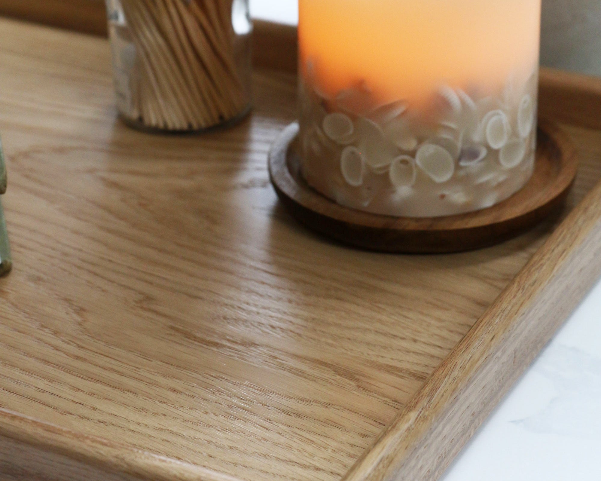 A decorative tray with a warm candlelit setting, used for organizing everyday essentials in a cozy interior space.