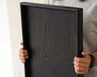 A wooden tray for footstool in use, being held to display its size and craftsmanship.