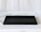 A close-up of a handcrafted tray, highlighting its sleek black finish and fine craftsmanship.