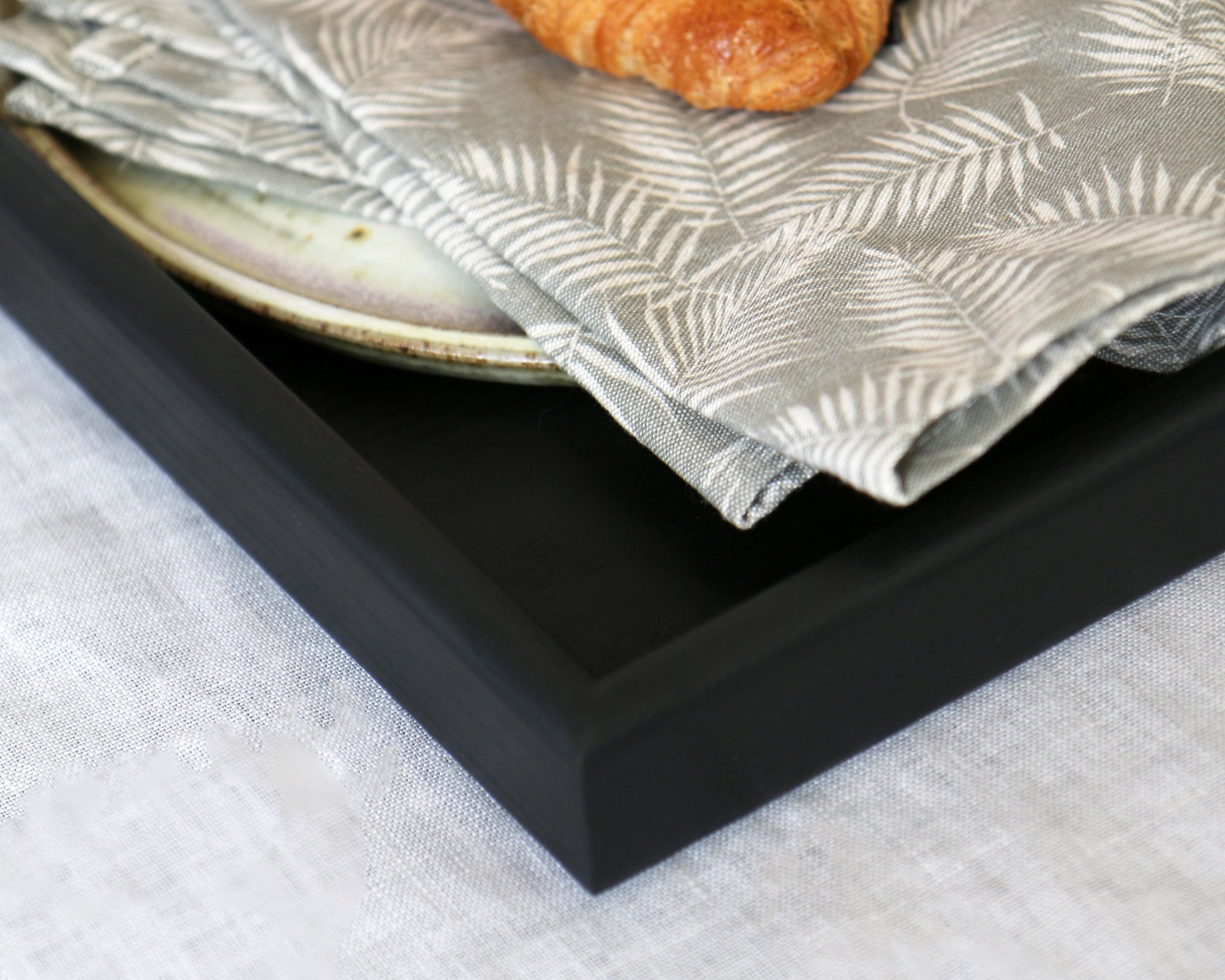 Close-up of a handcrafted tray, highlighting its smooth black finish and sharp edges, making it a stylish wooden tray for footstool or tabletop use.