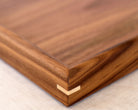 A close-up of the fine joinery and polished walnut surface of a wooden tray for footstool.
