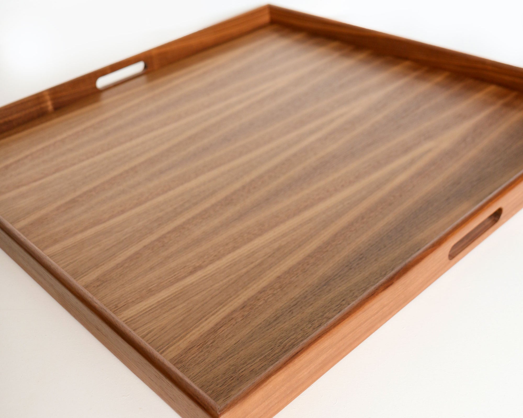 A large decorative tray in walnut with smooth, natural grain and built-in handles, designed for both function and style.