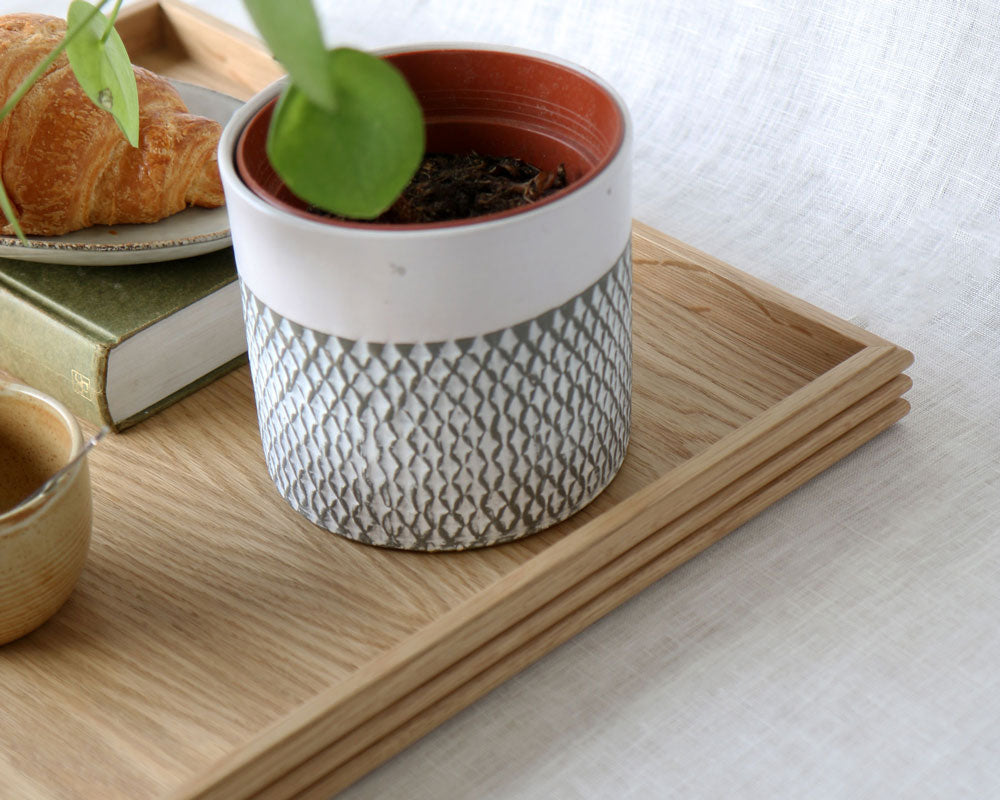 Close-up view of the oak tray corner showcasing the textured potted plant and the tray's smooth wood grain and fine craftsmanship.